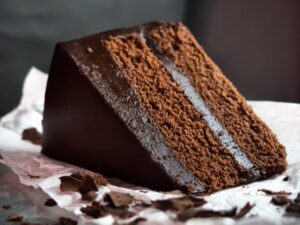 Chocolate cake slices on a plate, ingredients for a chocolate cake recipe, step-by-step cake preparation.