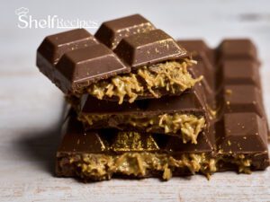 A close-up image of a rich, dark chocolate bar with a delectable filling of caramel and shredded coconut. The chocolate is smooth and glossy, with a hint of gold dust adding a touch of luxury. This is a Dubai chocolate bar, known for its exquisite combination of flavors and textures.