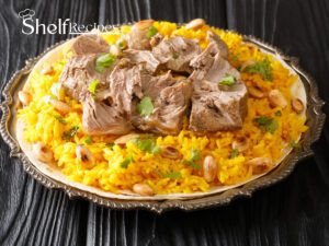 Jordanian mansaf dish with lamb on yellow rice, garnished with almonds and parsley, served on a decorative metal platter.